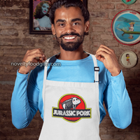 man-wearing-jurassic-pork-grill-dinosaur-park-meat-bbq-smoking-apron-mens-unisex-white-available-from-novelty-food-gifts-dot-com